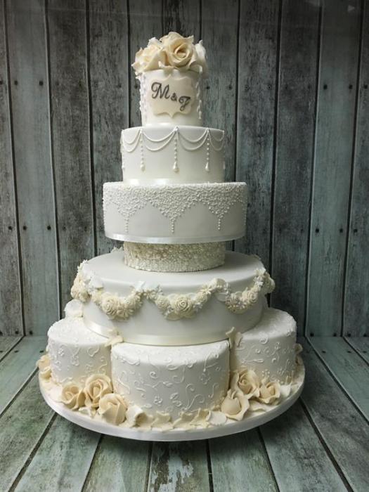 Extra large wedding cake personalised with initials of the couple sugar flowers hand piped pearls and old fashioned drop lines for for a truly timeless piece
