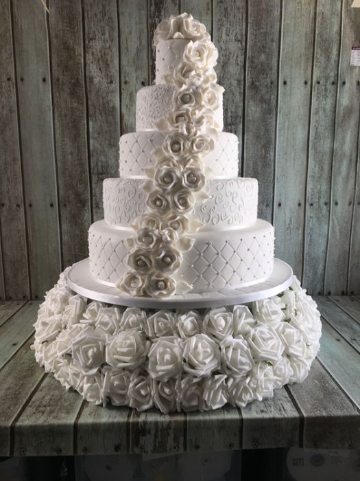 extra large wedding cake with cascading sugar roses on a cake stand of silk roses