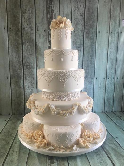 Extra large wedding cake with swags of flowers made of sugar half moons to have an unusual look and hand piped pearl To finish it off