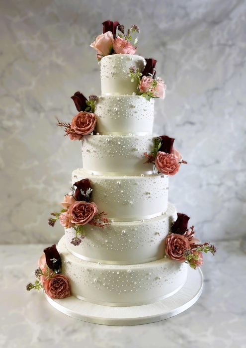Iced  large wedding cake with edible pearls and hand painted with silk flowers
