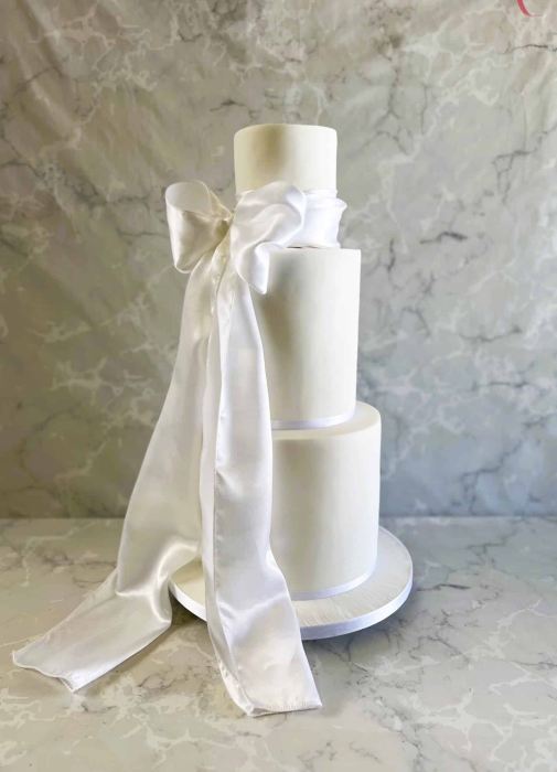 tall slender wedding cake with thick satin  draping sash