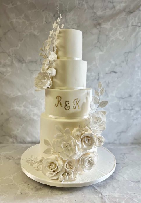 Tall wedding cake with oversized sugar flowers and ivy